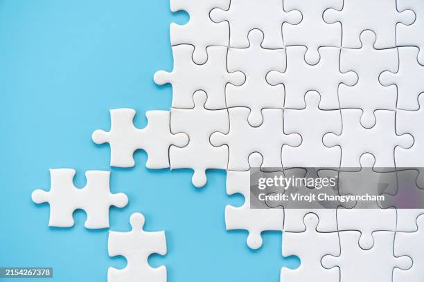 white puzzle jigsaw on blue background - puzzel stockfoto's en -beelden