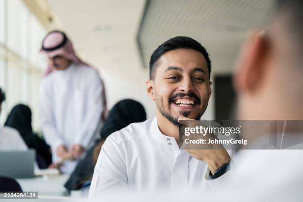 young saudi men interacting on university campus - arab people stock pictures, royalty-free photos & images