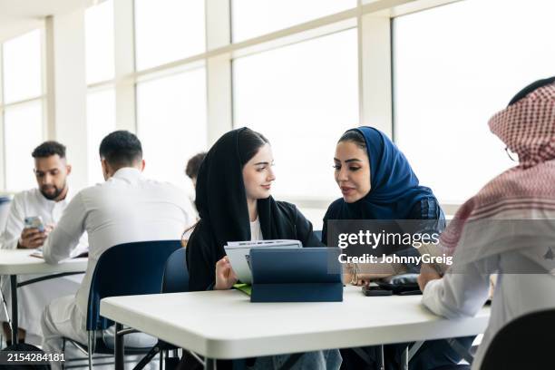 un jeune étudiant saoudien discute de son travail avec un instructeur - culture saoudienne photos et images de collection