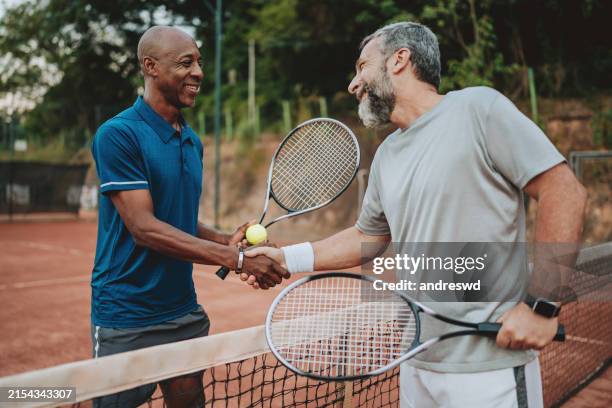 due amici che giocano a tennis si salutano alla rete - torneo di tennis foto e immagini stock