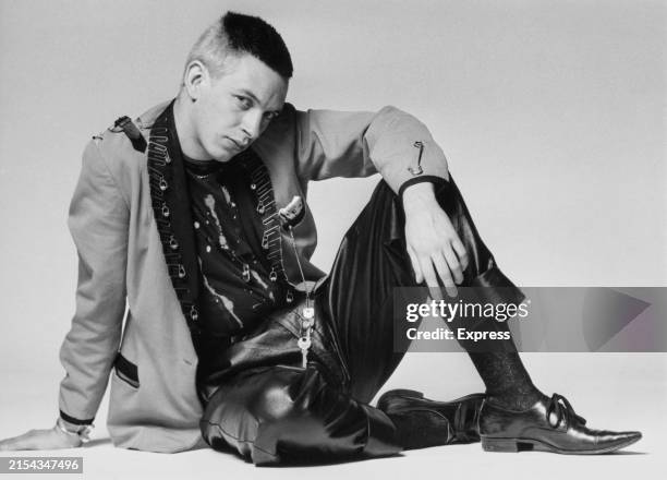 Fashion model wearing punk rock inspired outfit during a studio photoshoot, UK, 1976; he is wearing a bleach-stained t-shirt, a jacket with paper...