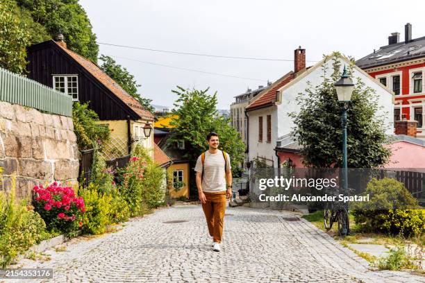 happy smiling man walking on damstredet street in oslo old town, norway - oslo foto e immagini stock