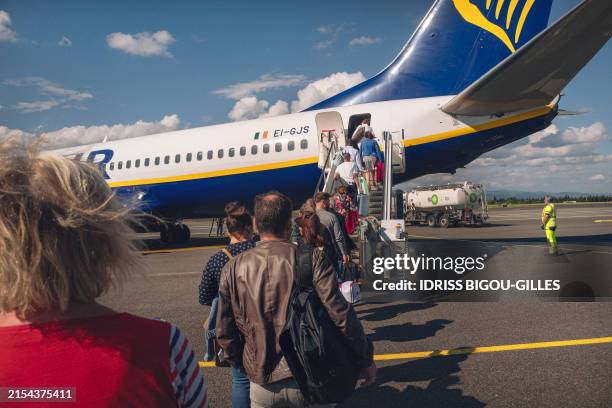 People walk to board a Ryanair plane heading to Porto in Portugal on the runway of Carcassonne airport in Aude, France on May 21, 2024.