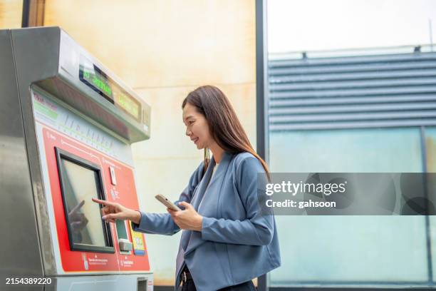 woman buying train ticket at kiosk - lightrail commuter stock pictures, royalty-free photos & images