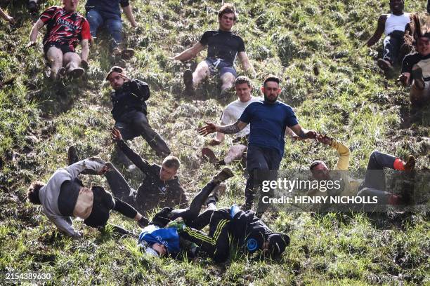 Competitors come tumbling down the hill in pursuit of a round Double Gloucester cheese during the annual Cooper's Hill cheese rolling competition...