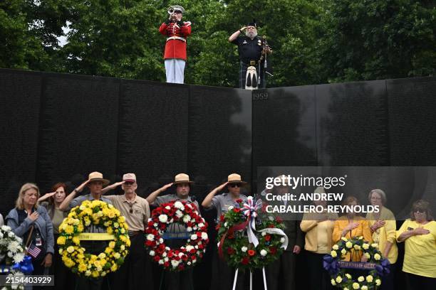 Military veterans, volunteers, and members of the National Park Service stand at attention during a wreath laying ceremony at the Vietnam Veterans...