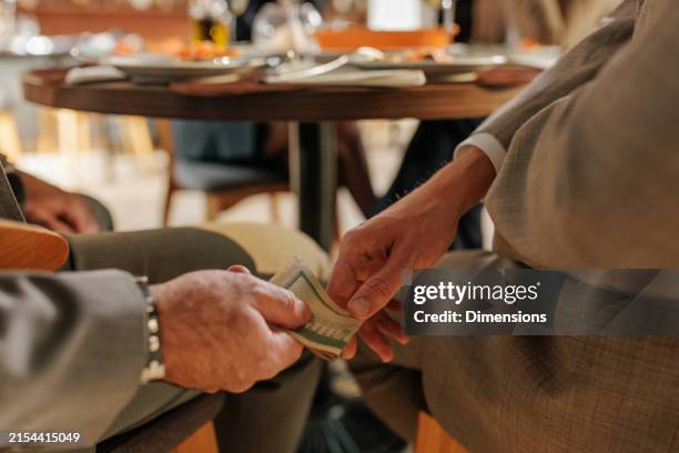 primer plano de un hombre de negocios dando dinero a un soborno. - soborno fotografías e imágenes de stock