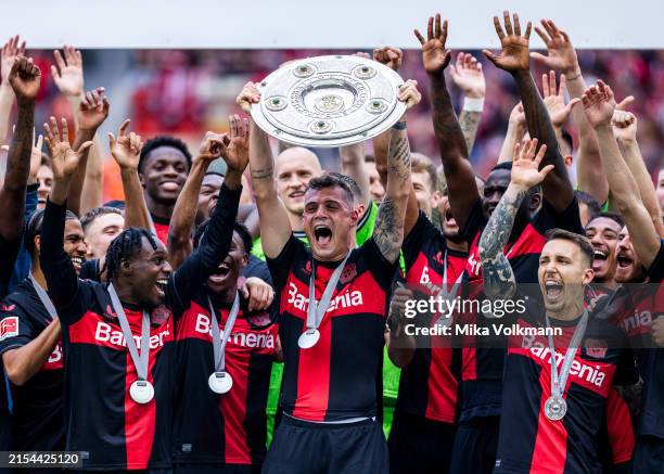 Granit Xhaka of Leverkusen celebrates the winning of championship trophy with Jeremie Frimpong of Leverkusen , Florian Wirtz of Leverkusen , Victor...