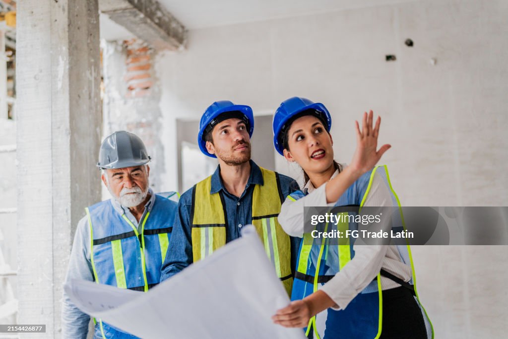 Coworkers talking and looking the blueprint in the house under construction