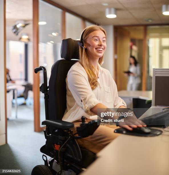 giovane donna disabile che lavora alla sua scrivania in un ufficio - sedia a rotelle foto e immagini stock