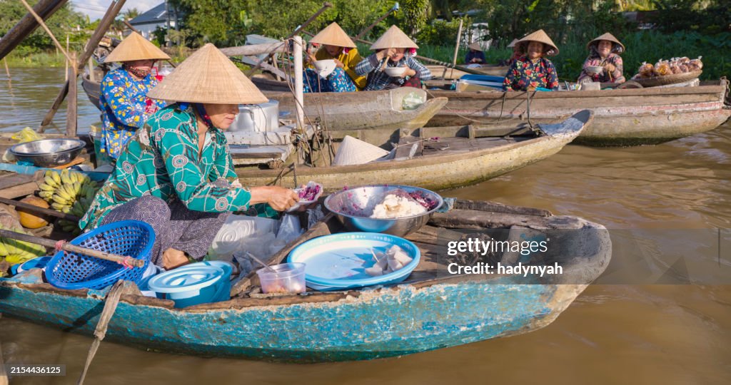 Vietnamese woman preparing coconut's snacks, floating market, Mekong River Delta, Vietnam