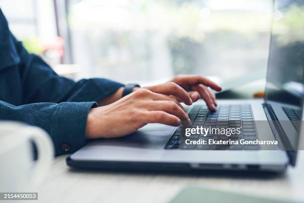 close-up of hands typing on a laptop keyboard. focus on fingers and laptop keys with blurred background. - tasto-di-computer foto e immagini stock