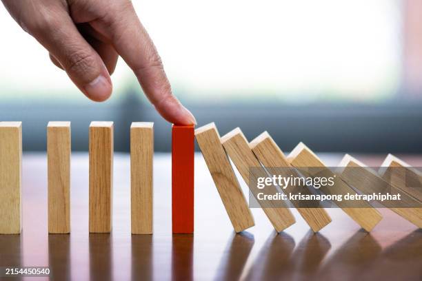 business woman hand stopping falling dominos in a business crisis management conceptual image. - block removal game stock pictures, royalty-free photos & images