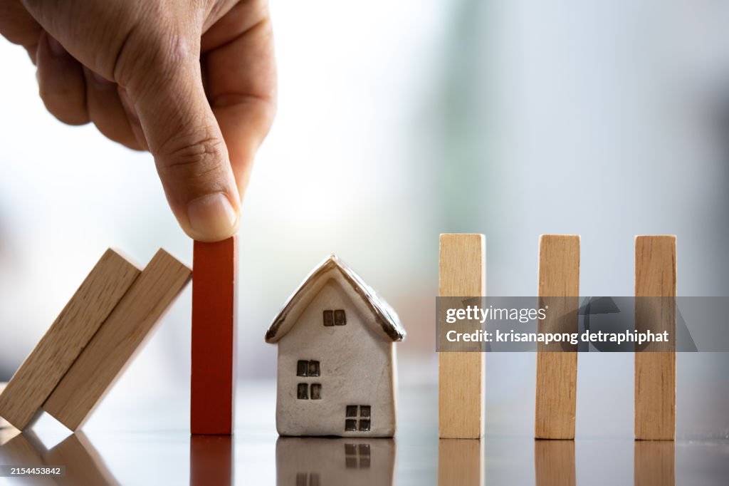 Business woman hand stopping falling dominos,Home insurance