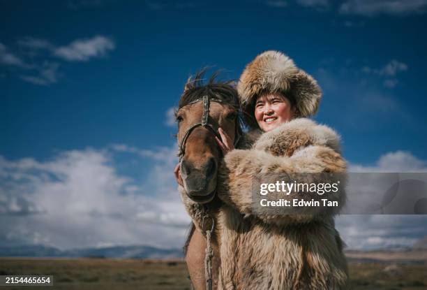 portrait young female kazakh eagle hunter together with her horse standing outdoor in bayan olgii, west mongolia - mongolian culture stock pictures, royalty-free photos & images