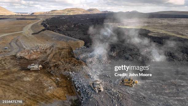 In this aerial view, bulldozers extend a berm to stop volcano lava flow on May 23, 2024 on the outskirts of Grindavik, Iceland. There have been a...