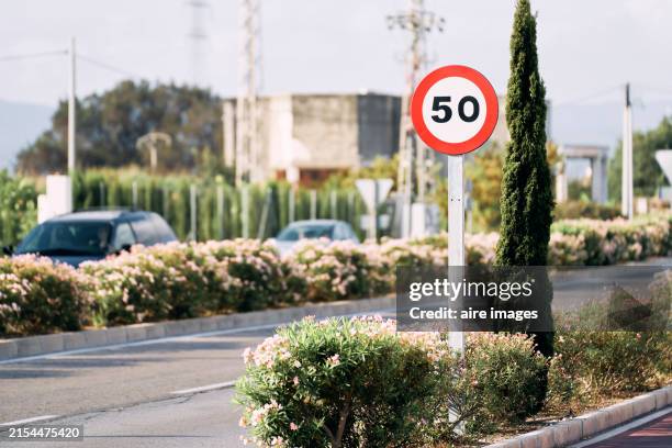 front view of a red round sign with a number inscribed on the street pole with cars on one side - número 50 imagens e fotografias de stock
