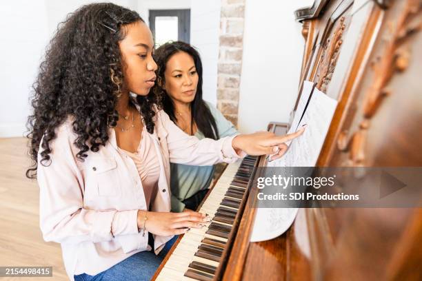 female teenager points to ask her piano teacher a question about the keystrokes she should make - piano bildbanksfoton och bilder