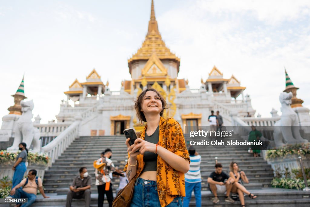 Woman using smartphone standing on the background of Wat Traimit