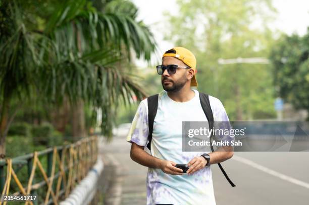 casual city walk: man with earbuds and backpack - in ear headphones stock pictures, royalty-free photos & images