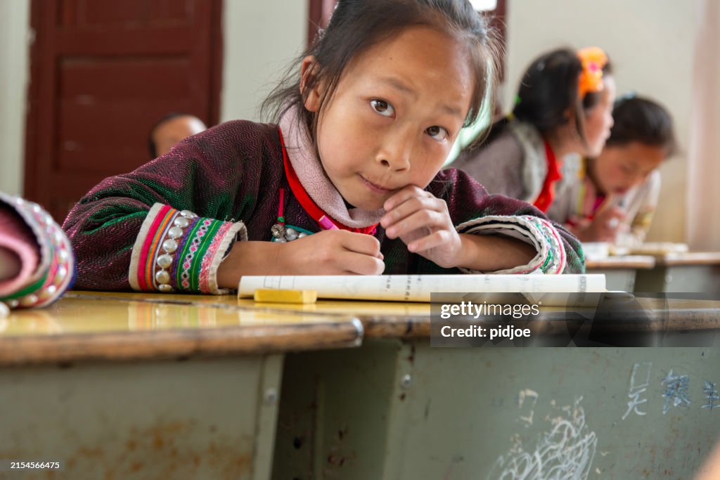 Concentrated Learner School, writing, looking at camera.