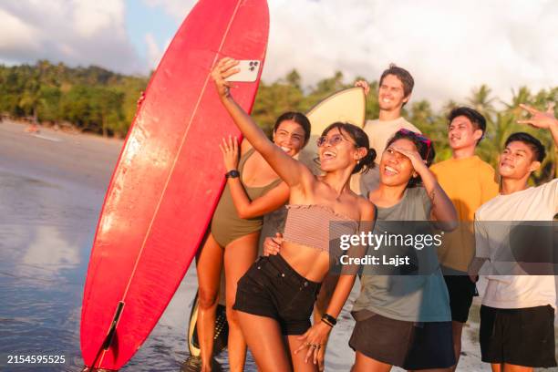 a group of people stand in shallow sea water with surfboards and take a selfie photo - philippines stock pictures, royalty-free photos & images
