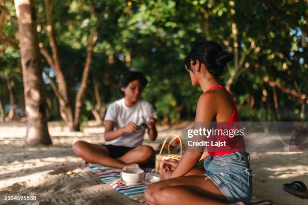 ein lesbisches paar genießt ein perfektes date - ein picknick am strand - philippinischer abstammung stock-fotos und bilder