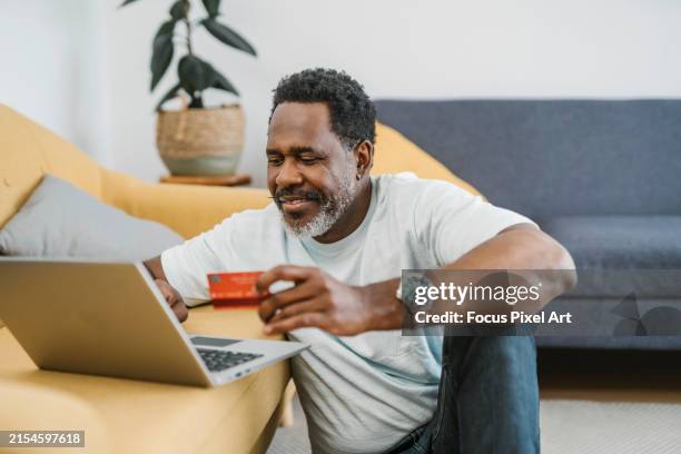 mature african man shopping online from home - credit card art stock pictures, royalty-free photos & images