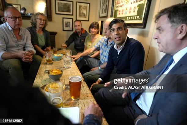Britain's Prime Minister and Conservative Party leader Rishi Sunak and Britain's Work and Pensions Secretary Mel Stride talk to community members...