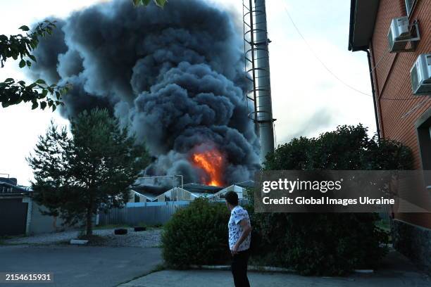 Man stands near residential building and looks on fire at hypermarket ‘Epicentr’ after Russian air attack on May 25, 2024 in Kharkiv, Ukraine....