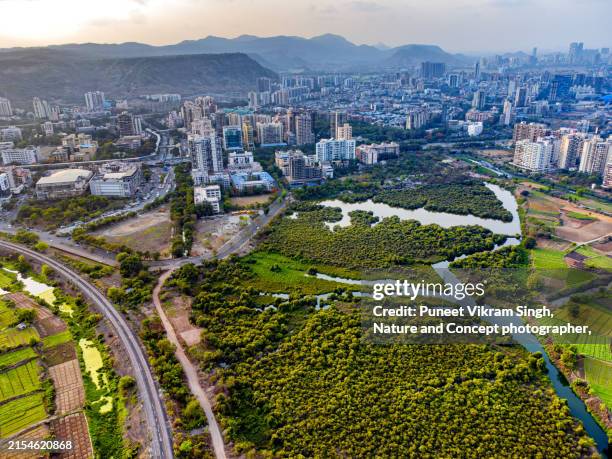 urban sprawl encroaching on fertile farmlands - a bird's eye view of progress at the expense of nature's bounty.
cultivated land in the backdrop of urban skyline. photo taken in kharghar, navi mumbai. - sunset point stock pictures, royalty-free photos & images