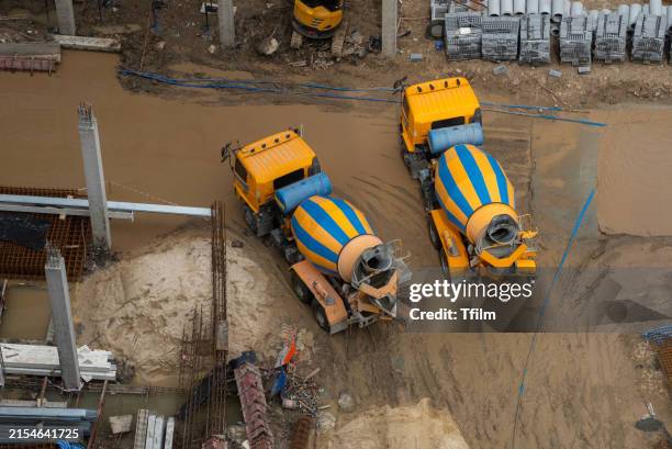 concrete mixer trucks at muddy construction site - mezclador-de-cemento fotografías e imágenes de stock