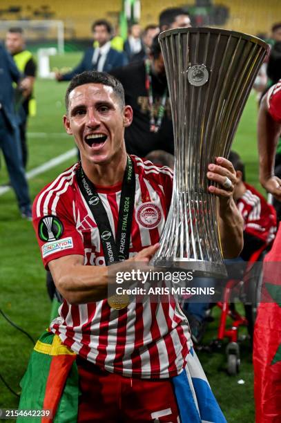 Olympiakos' Portuguese midfielder Daniel Podence holds the trophy after winning the UEFA Europa Conference League final football match between...