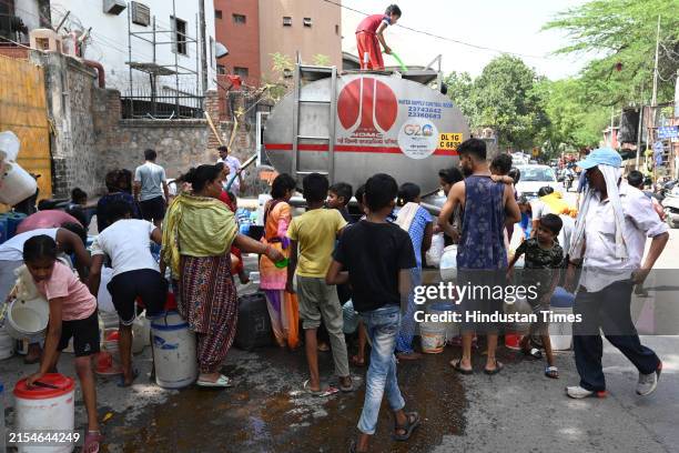 Locals collect drinking water from a tanker, amid a water crisis amid the summer months, at Sanjay Camp Chanakyapuri on May 29, 2024 in New Delhi,...