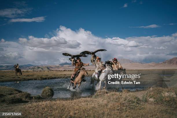 group of kazakh eagle hunters riding horses crossing river bayan olgii, west mongolia - mongolian culture stock pictures, royalty-free photos & images