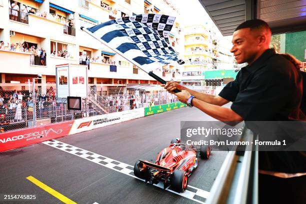 Race winner Charles Leclerc of Monaco driving the Ferrari SF-24 takes the chequered flag waved by Kylian Mbappe during the F1 Grand Prix of Monaco at...