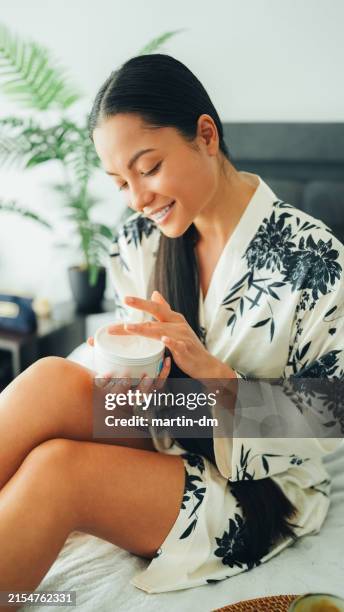 woman at home using shea butter body cream - shea butter stock pictures, royalty-free photos & images