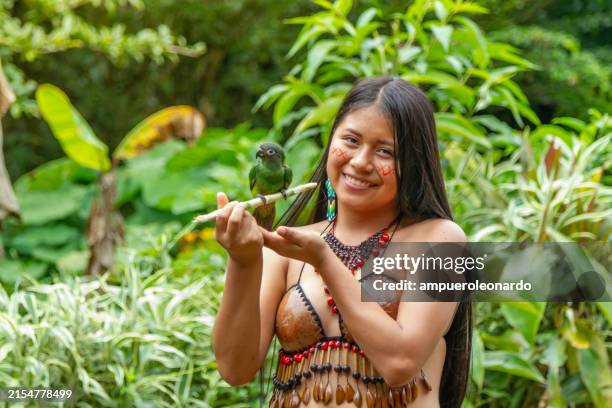 ein junges, wunderschönes indigenes frauenporträt, gekleidet in ihre traditionelle kleidung, während sie mit einem kleinen sittich / vogel spielt, der in ihrem tribu-dorf schießt. tribu quichua / kichwa napuruna. - fluss amazonas stock-fotos und bilder