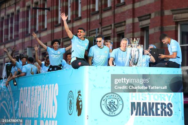 Matheus Nunes, Ederson, Erling Haaland and Rodri of Manchester City celebrate with the Premier League Trophy as the bus makes it's way down Deansgate...