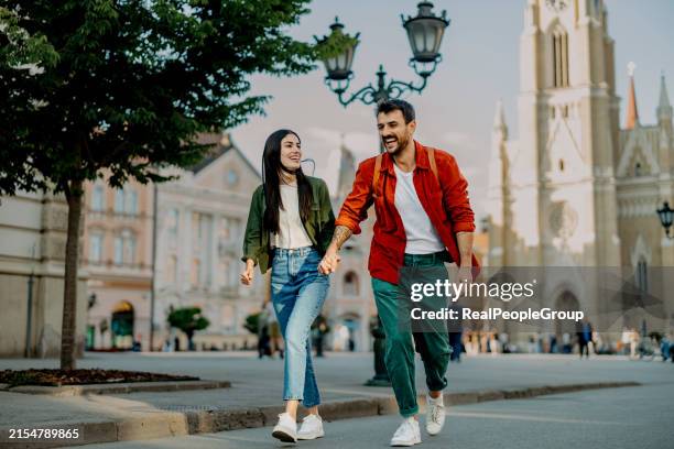couple playfully walking together in city - oost europese etniciteit stockfoto's en -beelden
