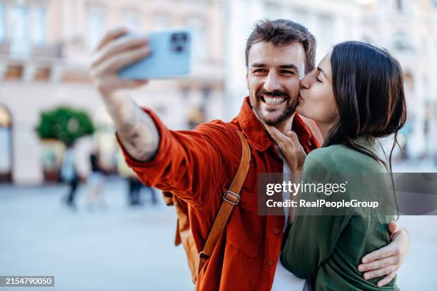 woman kissing man while taking a selfie - kissing phone stock pictures, royalty-free photos & images