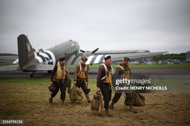 World War II reenactors walk away from a C-47, an aircraft that carried paratroopers over the drop zones in Normandy, France, at North Weald Airfield...