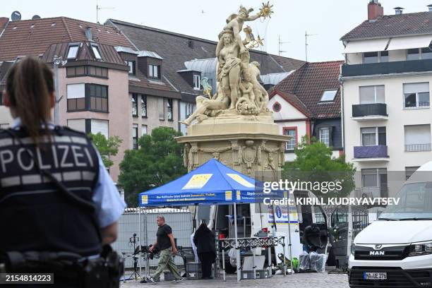 Police officer looks on as workers pack up the gear at the scene where several people were injured in a knife attack on May 31, 2024 in Mannheim,...