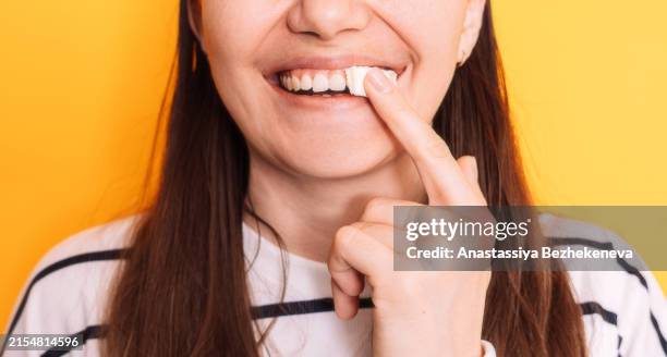 lady puts snus under her lip against yellow background - nicotina fotografías e imágenes de stock