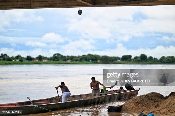 Men unload sand from a boat on the banks of the Apure River in San Fernando de Apure, Apure State, Venezuela, on May 31, 2024.