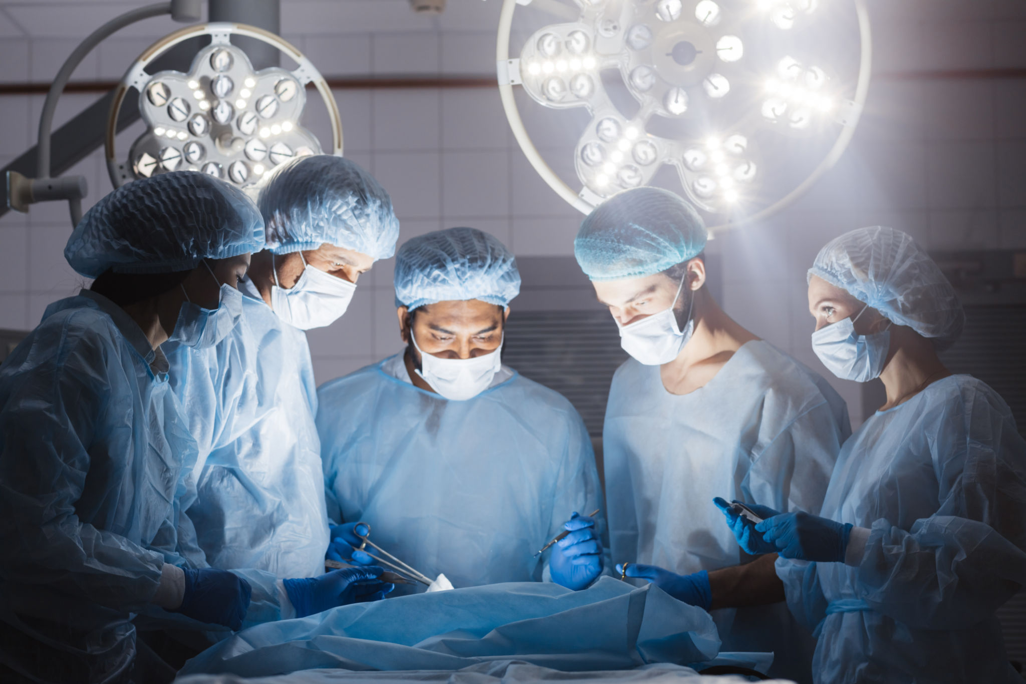 Doctors team in surgery in a dark background Doctors team in surgery in a dark background