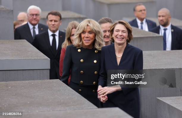 German First Lady Elke Buedenbender and French First Lady Brigitte Macron share a light moment while walking among stelae as German President...