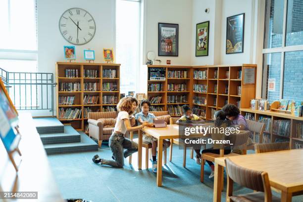 foto de gran angular de niños de la escuela con el maestro en la biblioteca, teniendo una clase de lectura - biblioteca fotografías e imágenes de stock