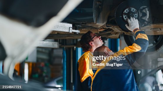 Professional mechanic repairing a car in auto repair shop. Professional mechanic repairing a car in auto repair shop.