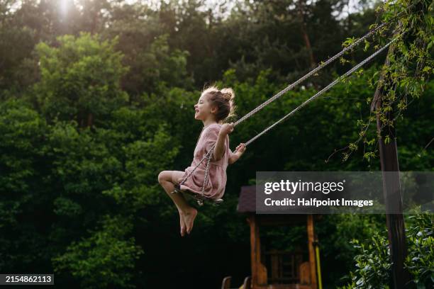 side view of beautiful girl swinging on garden swing. - number of people stock pictures, royalty-free photos & images